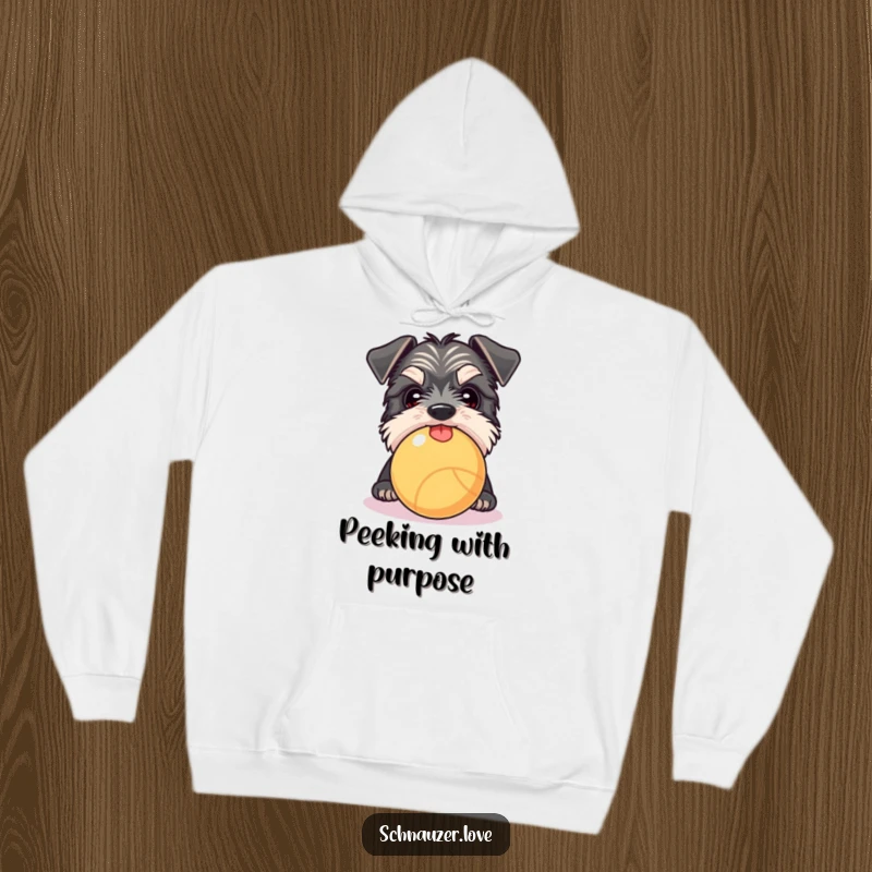 Funny Schnauzer hoodie showing a curious dog peeking over a ball with tongue out, perfect for cozy, humorous wear.